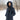 A woman in a forest wearing a long navy blue winter coat with the hood up