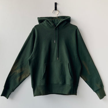 Green hoodie on a hanger against a white background