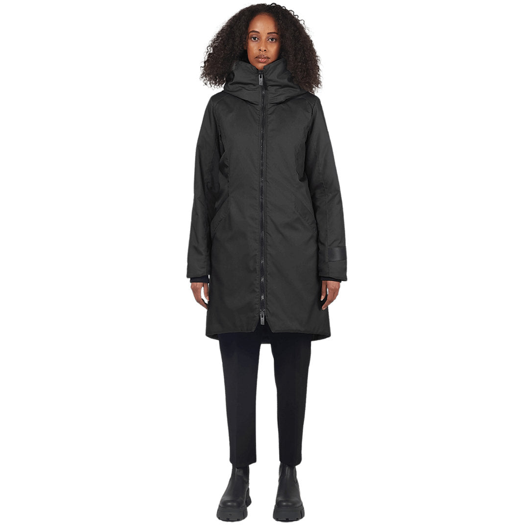 Female stands facing camera wearing a black parka on a white background