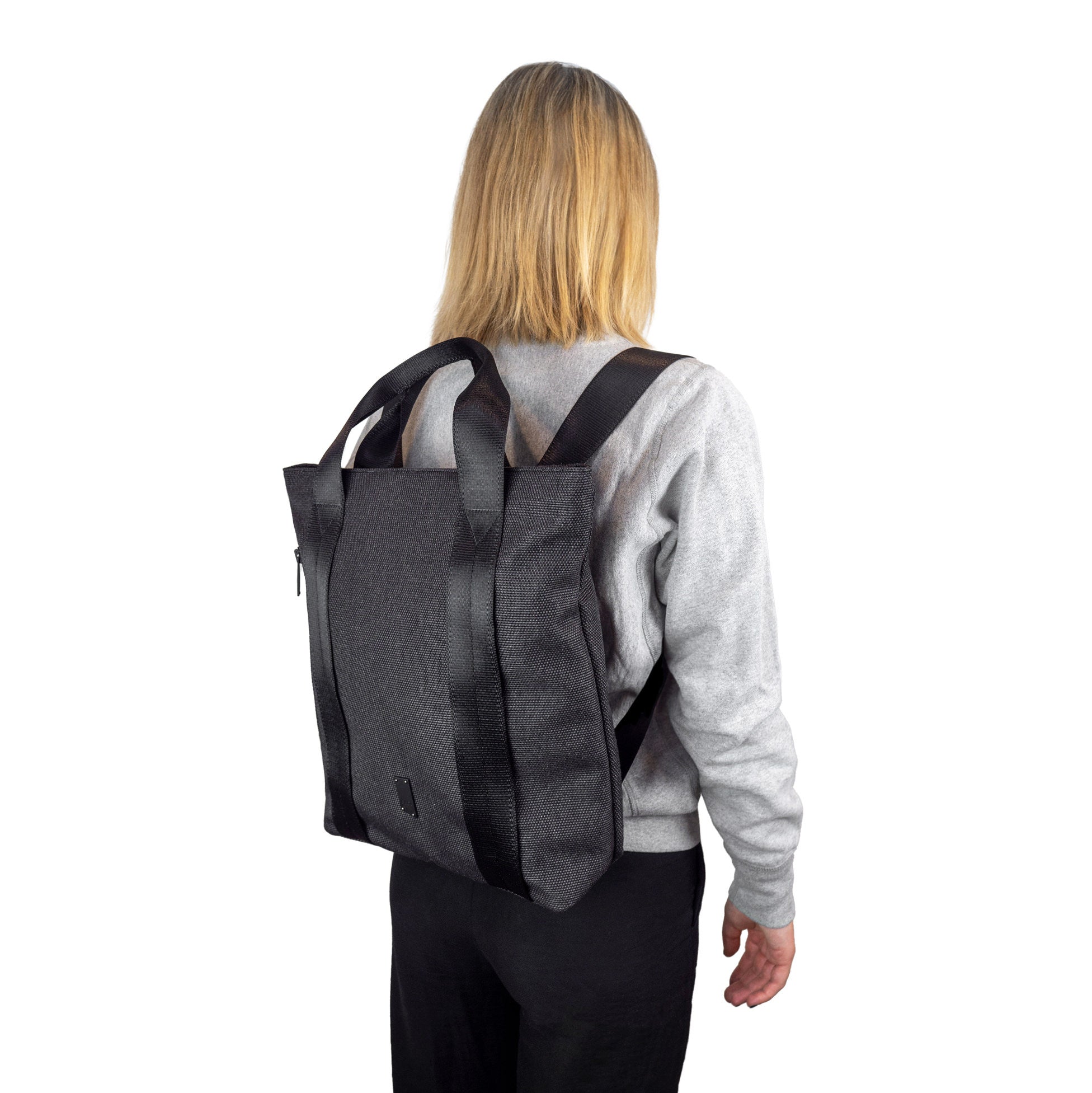 A female model wears the grey KITS as a backpack