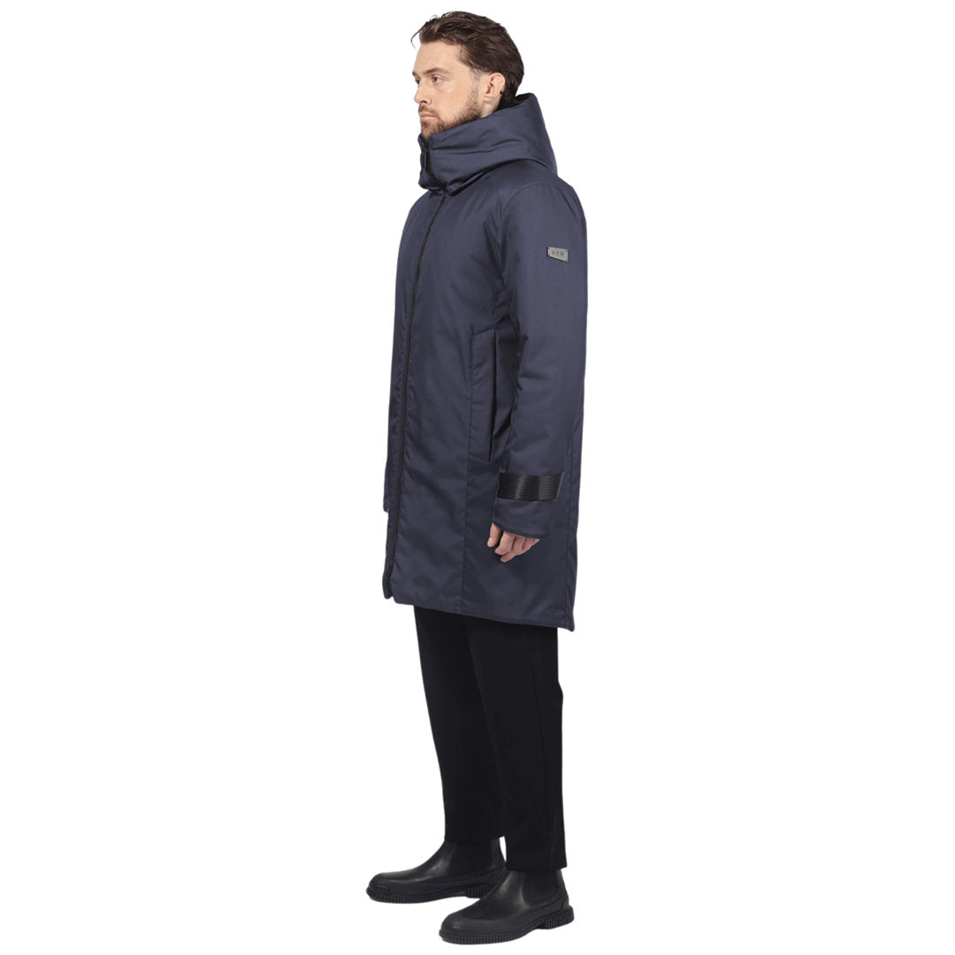 Male model stands side facing camera wearing a navy parka on a white background