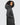 close of view of a woman wearing a long grey winter coat with a hood. Her hands are in her coat pockets