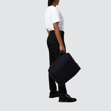 female model holding a backpack against a white background