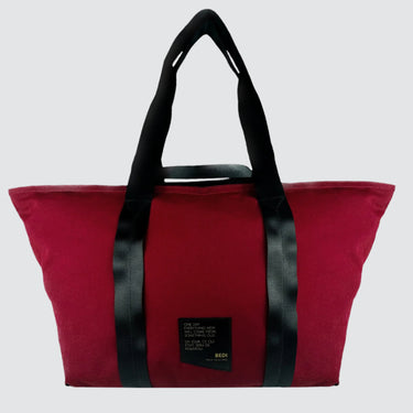 front view of a duffle bag in red twill material, against a white background.