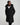 A woman wearing a black 3/4 length coat with the bottom zip unzipped
