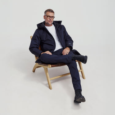 A man sitting in a modern chair wearing a navy winter coat