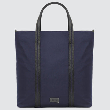 A large minimalist tote bag in navy nylon material, with a black strap that runs the height of the bag