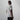 A man shown from the back wearing a light gray short-sleeve crewneck t-shirt and black pants, standing against a plain light gray studio background.