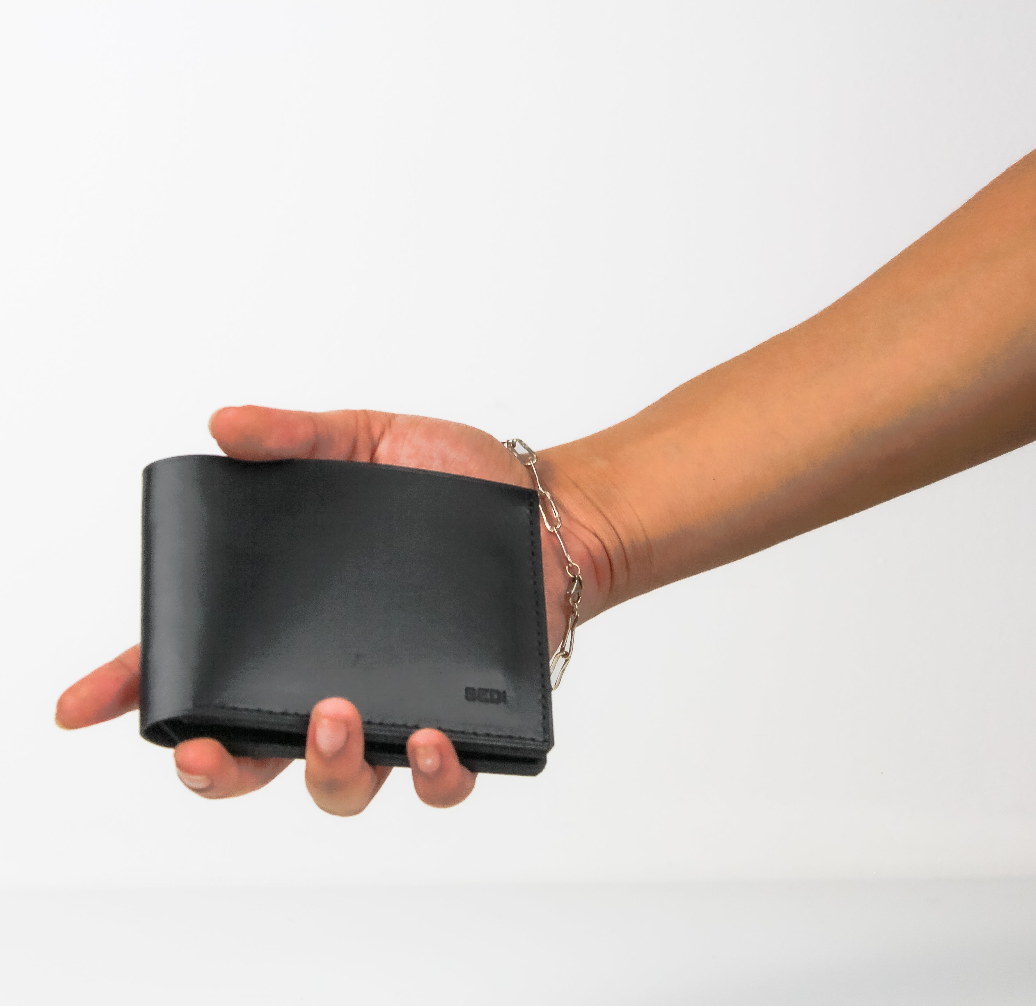 Black leather wallet held in a woman's hand, with a white background