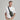 A man wearing a white t-shirt and khaki pants models an olive green sling bag with a black strap against a solid gray studio background.