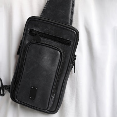 a close up of a black leather bag against a white shirt