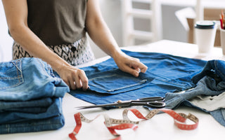 a woman attempting to repair and up cycle her pair of jeans