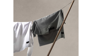 sustainable cotton shirts in graphite and white on a drying chord.