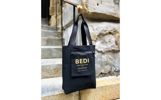 an image of the reversible tote bag displayed inside out showing off the inside pocket logo, pictured on outside stairs and a stone wall