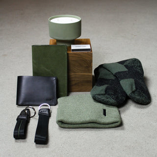 A staged assortment of small gifts, including a candle, socks, two wallets, two keychains and a beanie
