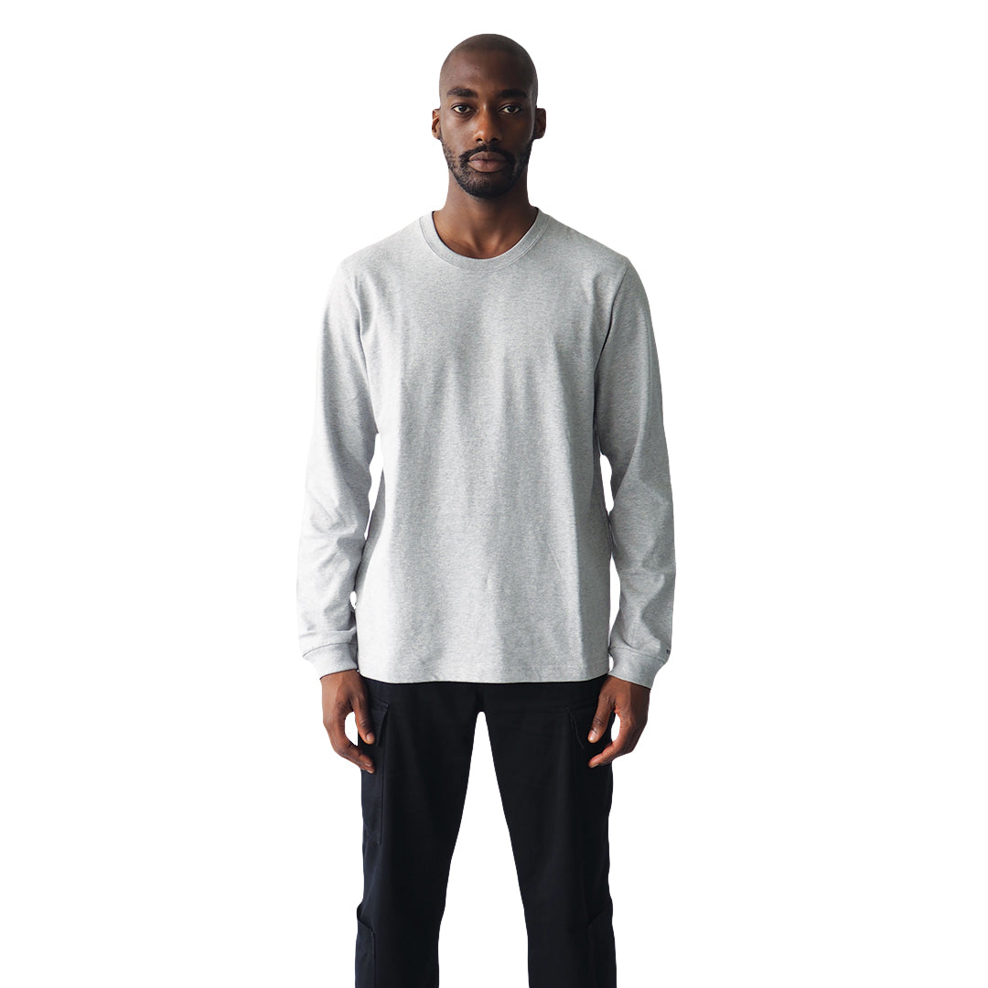 a male model stands, facing the camera wearing a Grey light long sleeve tee on a white background