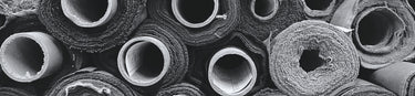 Side view of different types of rolls of fabric, stacked. Black and white 