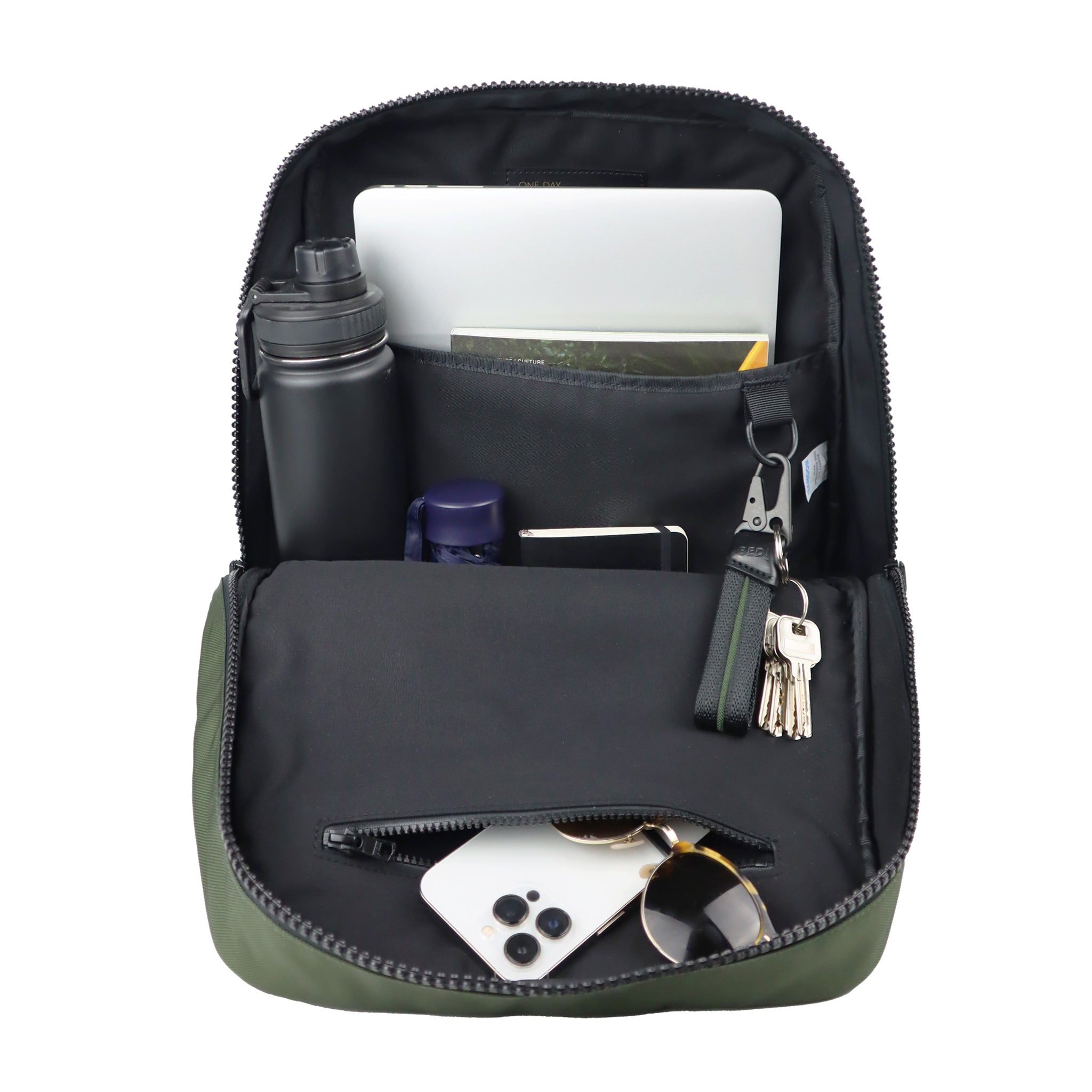 The CHE backpack with the main compartment open, showing the contents. Contents include: a water bottle, umbrella, magazine, laptop, iPhone, sunglasses and keychain. 