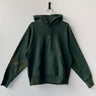 Green hoodie on a hanger against a white background