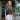 A woman stands in front of a store wearing a brown tshirt and a black leather fanny pack