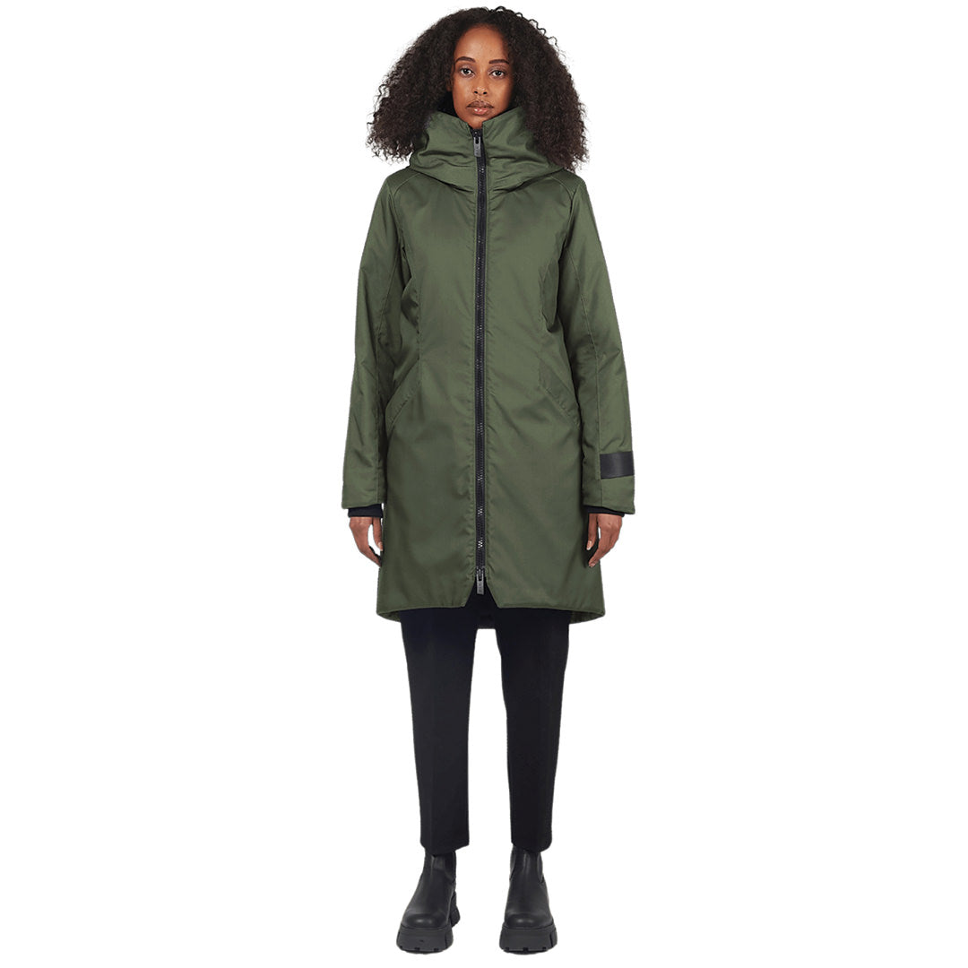 Female stands facing camera wearing a evergreen parka on a white background