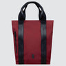 Tote bag made with red twill material. There is a vertical black zipper on the left side, and the black seatbelt straps continue all the way down the front of the bag