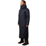 A man wearing a long navy blue winter coat with a hood and simple design