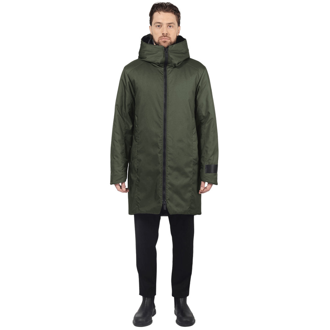 Male model stands facing camera wearing a evergreen parka on a white background