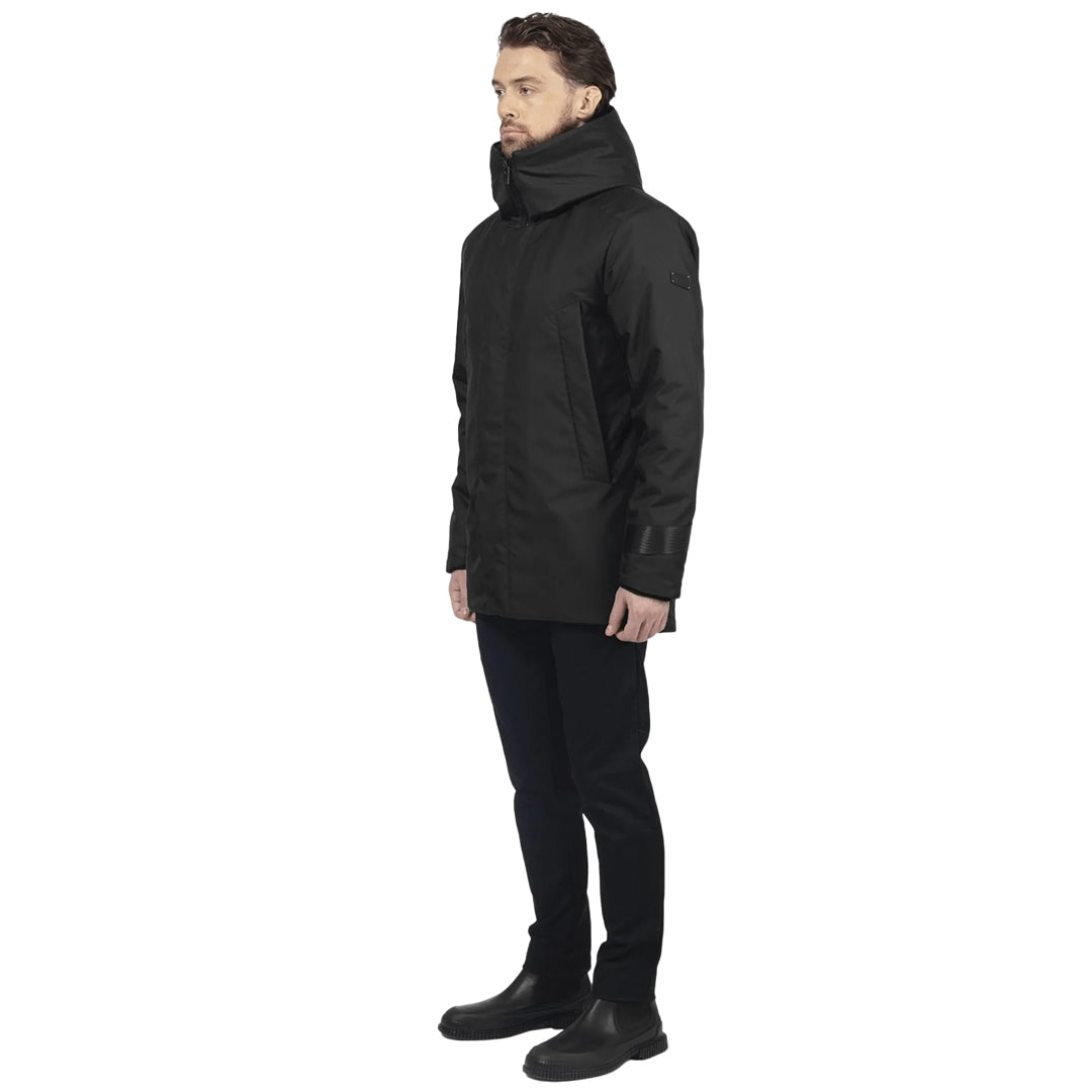 male model stands on side profile, wearing a black utilitarian style waist length jacket on a white background.