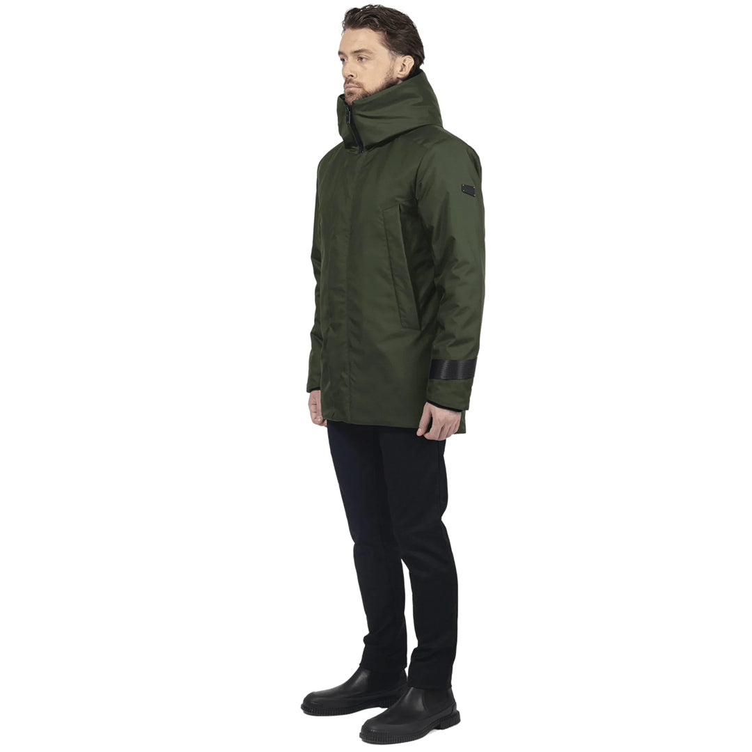 male model stands on side profile, wearing a green utilitarian style waist length jacket on a white background.