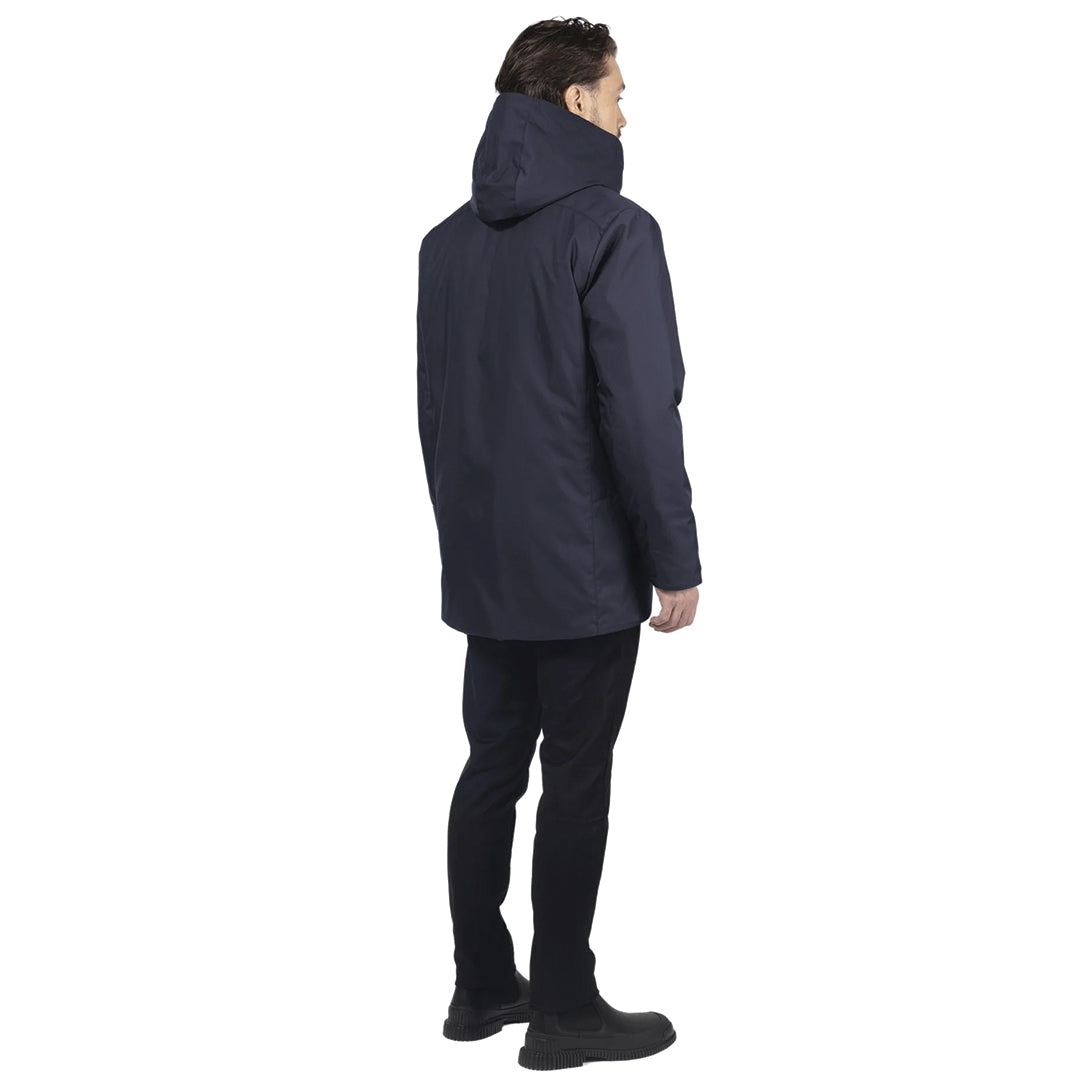 male model stands so his back faces us, wearing a navy utilitarian style waist length jacket on a white background.