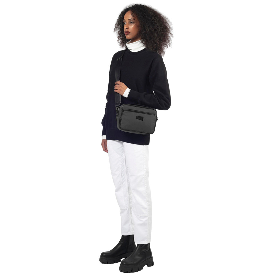 female stands facing the camera wearing the goodall + bag in grey as crossbody on a white background