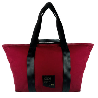 front view of a duffle bag in red twill material, against a white background.