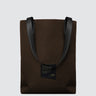 Brown tote bag with black handles on a light gray background