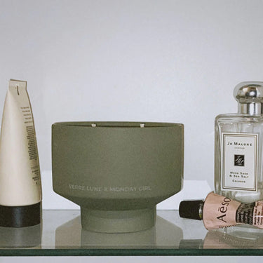 Lifestyle picture of Verre Lune the 5pm candle.  Hanging from a bathroom shelf amongst other bathroom necessities.