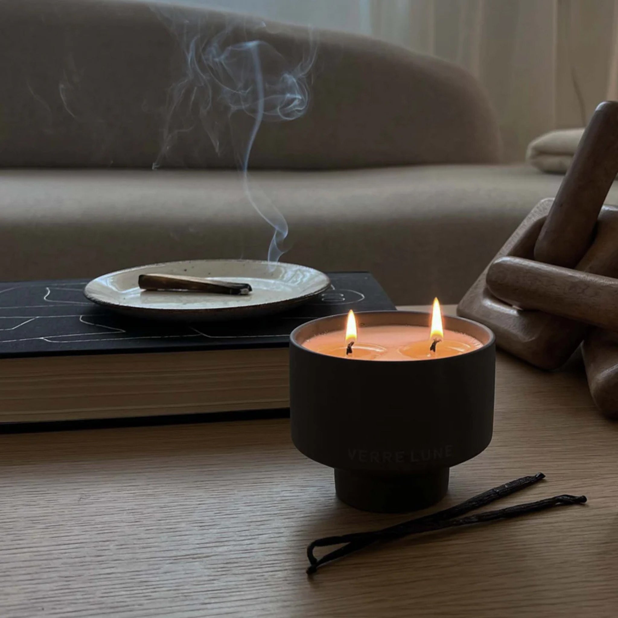 a candle lit with sage burning by its side in a modern living room setting