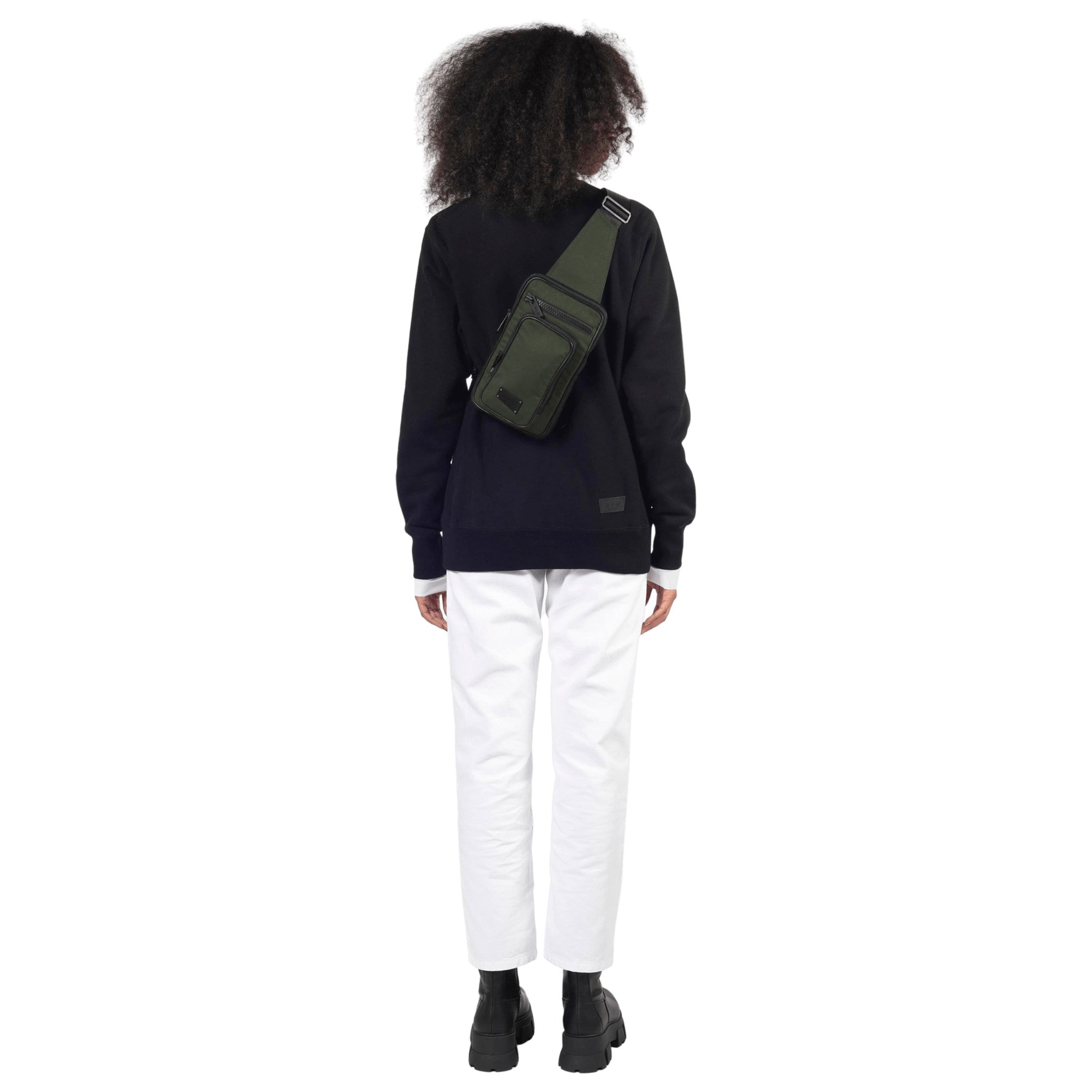 female stands back to camera showing off the watson crossbody back in evergreen on a white background