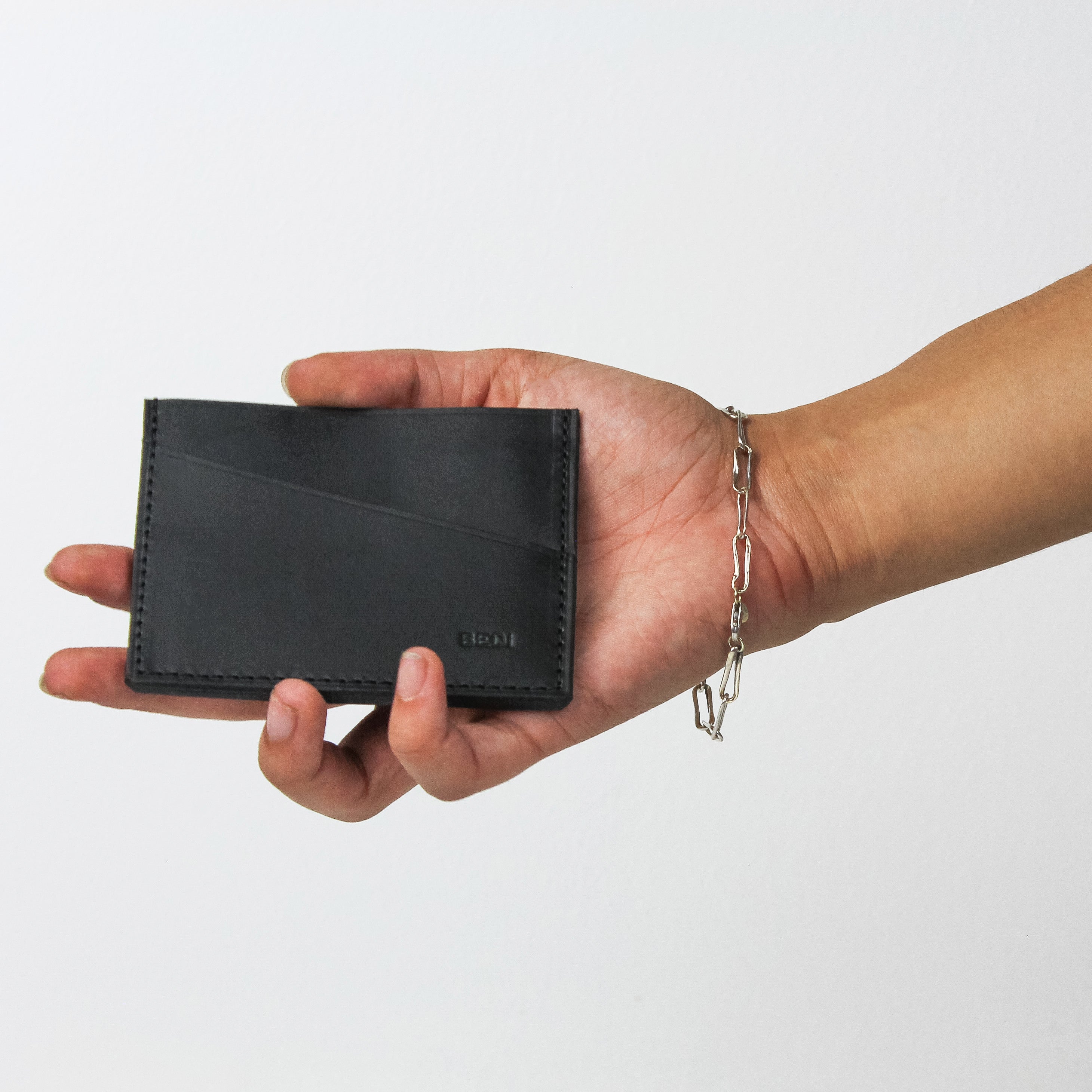 Bedi's black leather card holder held in a woman's hand