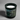 A candle in a black jar with a green forest label on a concrete background