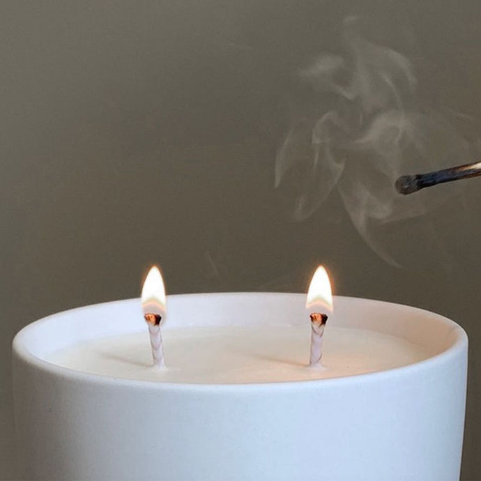 A close up view of a large candle with two wicks, both lit