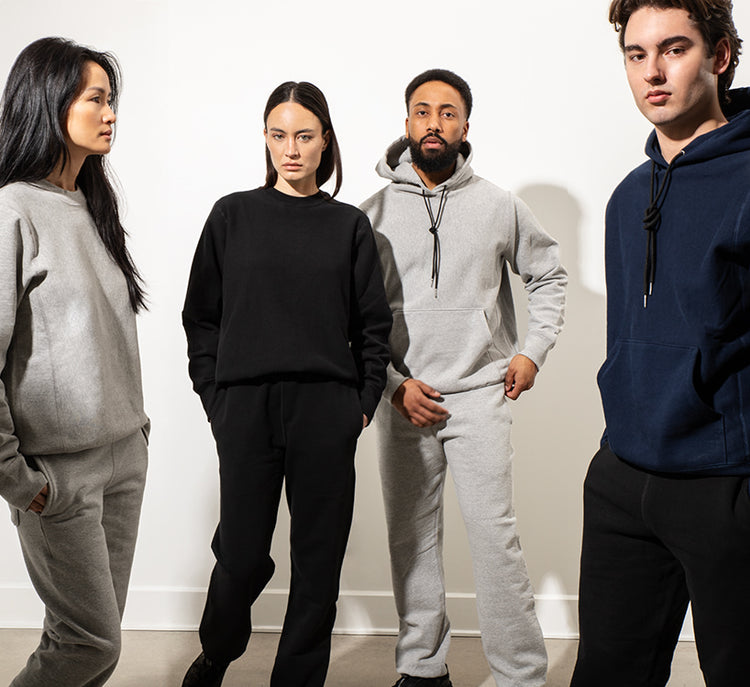Two male and two female models stand in front of a white wall wearing a variety of Bedi sweaters and sweatpants