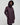 Woman wearing a long dark purple coat with a hood on a light grey background