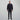 Man wearing a navy 1/4 zip sweater and black pants on a grey background