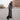 a man in a long grey winter coat walks across a street in Montreal