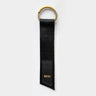 A simple keychain made from a black seatbelt, with gold brass ring and a faux leather logo patch with gold letters