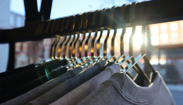 Sweaters hanging on gold hangers, backlit by the setting sun