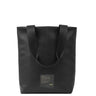 A minimalist black vegan leather tote bag, with a black patch on the lower middle 
