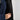 Person opening an inner zip pocket in a vest against a light grey background