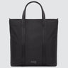 A large minimalist tote bag in black nylon material, with a black strap that runs the height of the bag