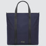 A large minimalist tote bag in navy nylon material, with a black strap that runs the height of the bag